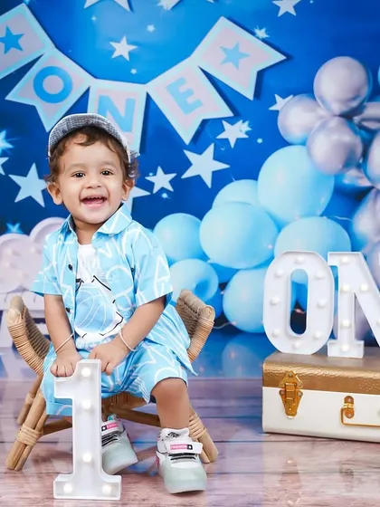 A bright, happy smile from the birthday boy. The light-up "ONE" sign is a popular prop that adds a celebratory feel to the photos.