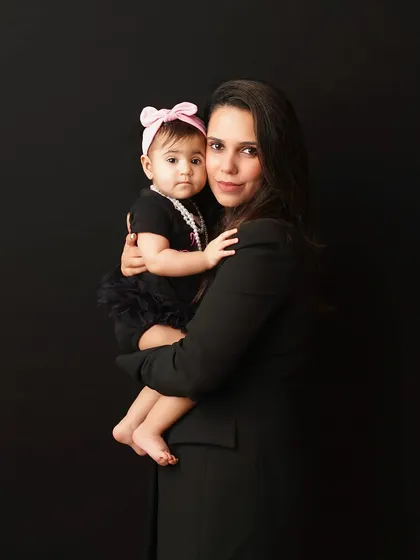 A classic mother-daughter portrait. The direct gaze and simple black background create a strong, elegant image that highlights their connection.