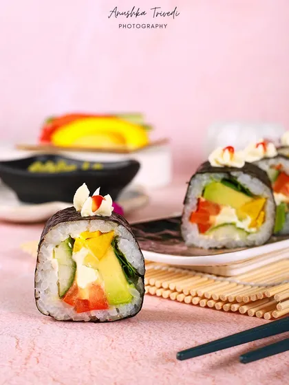 Veggie sushi rolls on a pretty pink background. The soft colour palette and delicate styling give these sushi shots a fresh, light, and almost whimsical feel.