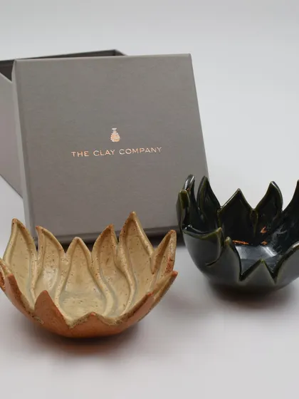 A set of two lotus bowls, one in a natural speckled glaze and the other in a deep green, shown with their custom gift box. This makes for a perfect, ready-to-give present.