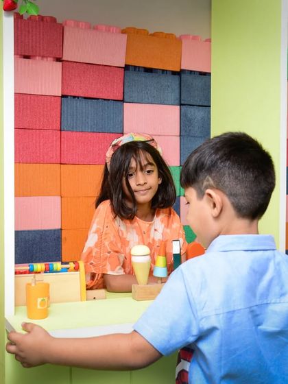 A customer carefully considers his options at the pretend play counter. These interactions are wonderful for developing imagination.