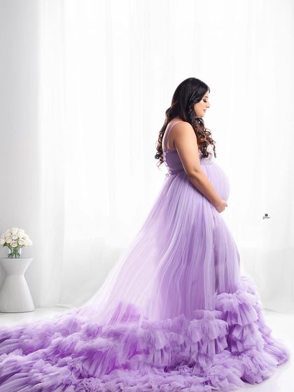 A serene portrait in a beautiful lavender gown against a bright, airy background. The soft light from the window creates a gentle and peaceful mood.