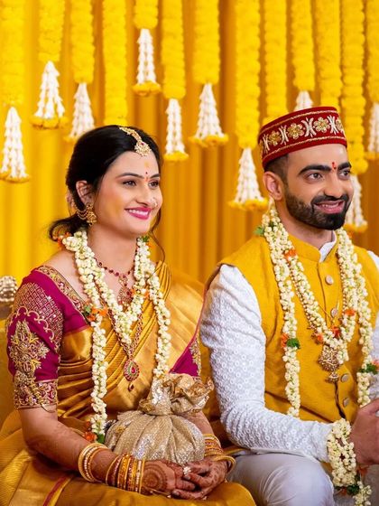 The happy couple is surrounded by cascading marigolds and tuberose bunches. These hanging floral lines create a mesmerizing and traditional backdrop, weaving a tale of love in a vibrant Haldi celebration.