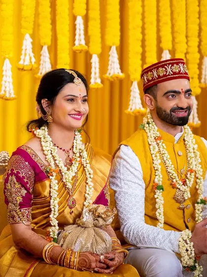 The happy couple is surrounded by cascading marigolds and tuberose bunches. These hanging floral lines create a mesmerizing and traditional backdrop, weaving a tale of love in a vibrant Haldi celebration.
