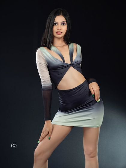 A full-length view of a modern, cutout dress against a stark black background. The studio lighting is focused on the model, making the colors of the dress and her confident stance the main features.