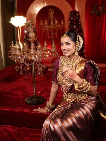 Seated in a regal setting, this bride's look is completed by a beautiful candelabra and a rich, red backdrop.