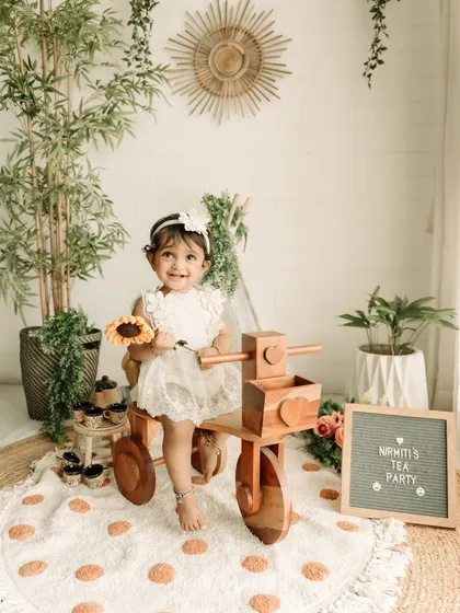 A happy smile from the birthday girl on her wooden tricycle, surrounded by boho-chic decor.