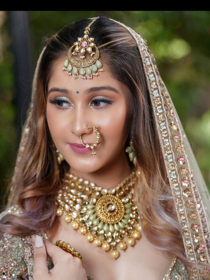 A close-up on the makeup and the stunning mint-green accented maang tikka and nath.