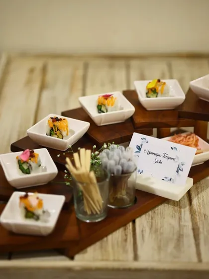 A beautiful display of Asparagus Tempura Sushi on a tiered wooden stand. This presentation style is perfect for passed appetizers, allowing guests to easily enjoy our creations.