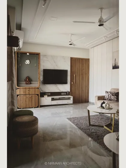 In this living room, we combined a marble-clad media wall with a wooden pooja mandir. This creates a harmonious balance between modern aesthetics and traditional values, all within a clean and uncluttered layout.