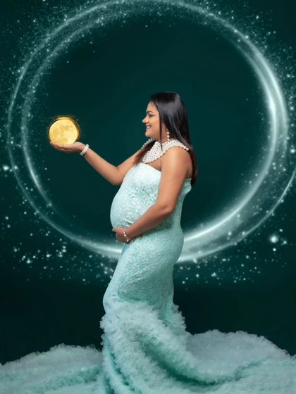 The pregnancy glow all around. This celestial portrait features a mother-to-be holding a glowing moon against a starry, ringed backdrop.