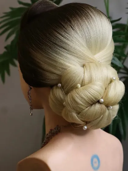 A knot bun hairstyle, which is an excellent choice for medium to short hair. The knotting technique helps to create a full and voluminous bun, adorned here with pearls.