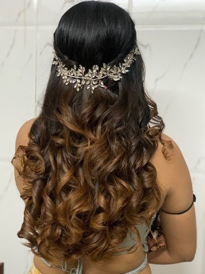 Beautiful textured curls for a bridesmaid. This half-up hairstyle is accentuated with a stunning crystal hairpiece, creating a look that is both glamorous and elegant for her sister's wedding.