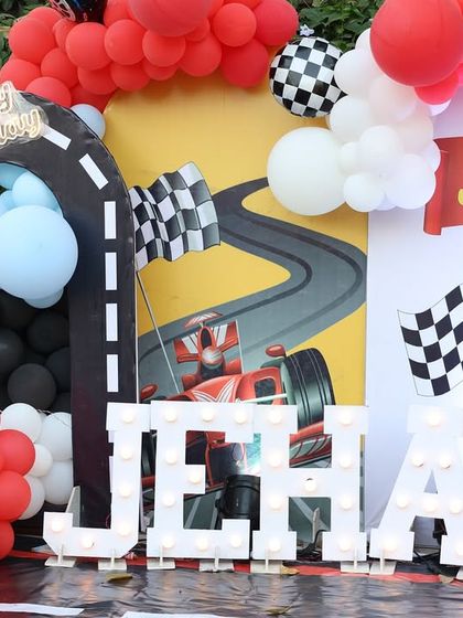 A close-up of the light-up 'JEHAN' letters and the detailed car-themed backdrop. Custom lighting adds a fantastic touch to any decor setup.