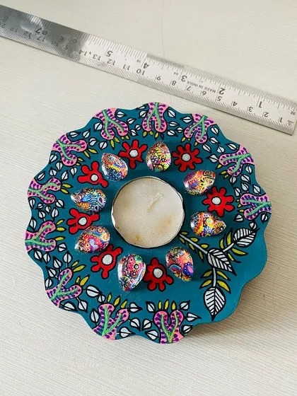 This floral-shaped candle holder is painted in a deep teal, with my signature patterns and colorful art cabochons surrounding the candle.