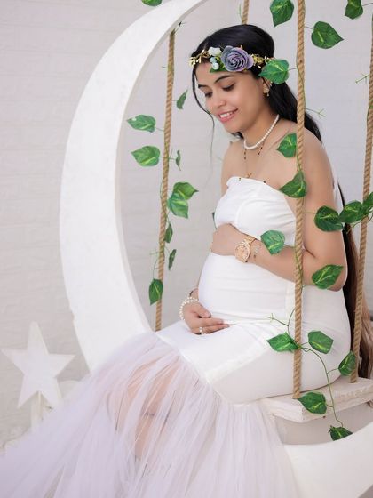 A serene portrait on our moon swing. The all-white outfit and the gentle way she holds her baby bump create a pure and angelic look for her maternity photos.