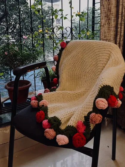 This is my rose bouquet blanket, a true passion project. I stitched 32 individual roses onto this cozy, cream-colored blanket, creating a piece that is both functional and a work of art. It’s perfect for draping over a chair or snuggling up with.