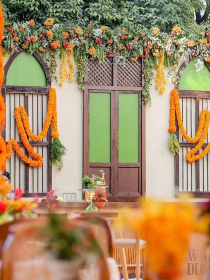 A view of the event space showing the 'haveli' backdrop, dining tables, and the intricate marigold jaal on the left. This gives a good sense of the overall layout.