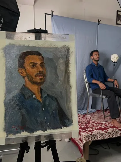 This is what a live portrait session looks like. Here, you can see the finished oil portrait of Satyam on the easel, with him posing in the background. These sessions are an immersive experience where we work together to create something truly personal.