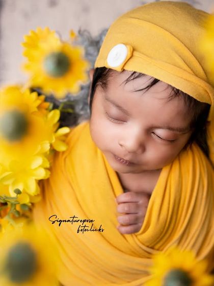 A little ray of sunshine. This newborn boy is wrapped snugly in yellow and surrounded by sunflowers, creating a bright, cheerful, and heartwarming portrait.