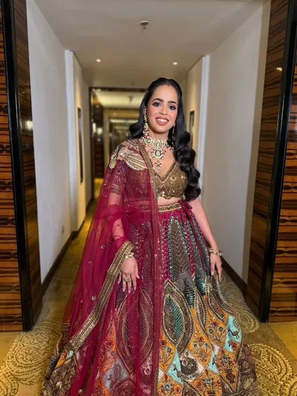 A full-length shot capturing the entire bridal ensemble. The makeup, with its defined eyes and sculpted glow, perfectly complements the intricate, multi-colored lehenga.