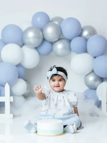A beautiful portrait of the birthday girl waving, sitting in front of a lovely balloon arch. We make sure to capture posed and candid shots.