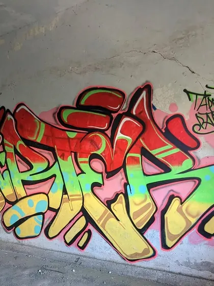 A red, gold, and green piece painted in a concrete underpass. The raw location adds to the authentic feel of this classic graffiti lettering.