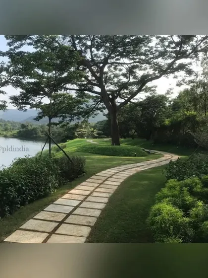 This stone pathway follows the curve of a rolling lawn, leading towards a large, shady tree by the water's edge. It invites a leisurely stroll to enjoy the magnificent views and peaceful atmosphere.