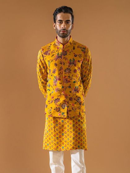A full-length view of the yellow floral jacket and patterned kurta set. This ensemble tells a story of tradition and panache, perfect for the man who wants to stand out.