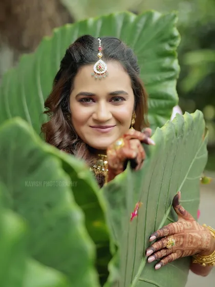 A playful bridal portrait, with the bride peeking through large green leaves.