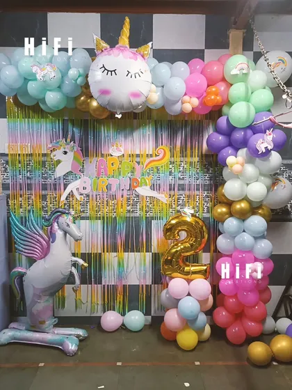 A whimsical unicorn-themed birthday setup with a large winged unicorn balloon and a rainbow-colored backdrop.