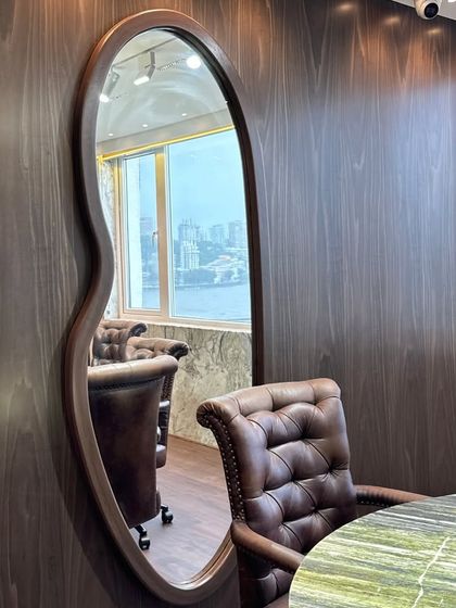 A custom-shaped, wood-framed mirror adds an element of organic elegance to the conference room, reflecting the space and the stunning sea view outside.