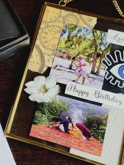 A close-up of a handmade vintage glass frame, decorated with photos, an evil eye charm, and papercraft elements for a layered, scrapbook feel.