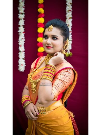 A side profile of a traditional look, highlighting the contouring and the way the makeup complements the intricate gold jewelry. The hairstyle is a neat bun, keeping the focus on the face and accessories.