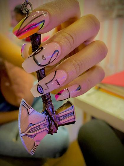 A unique, abstract design on long coffin nails. The sheer base is decorated with black line art and pops of neon color, shown here held with a Thor's hammer keychain.