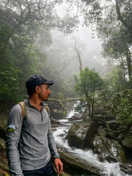A trekker stands by a misty stream in the forest section of the Bandaje trek. The atmosphere here is magical.