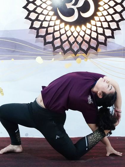 A deep backbend in a kneeling position, showing excellent spinal flexibility and strength.