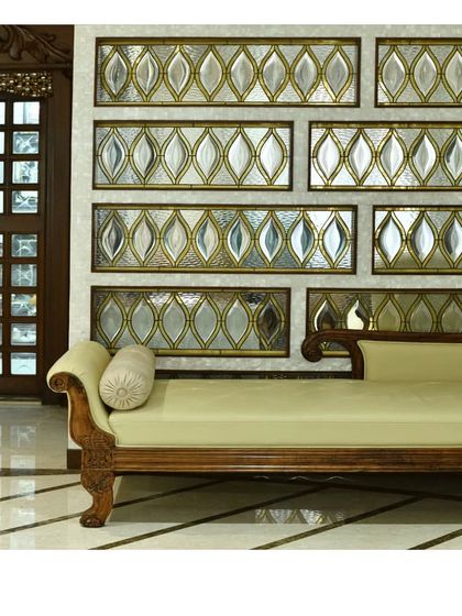 A beautiful seating nook featuring a classic divan set against a wall of custom-beveled glass panels with brass detailing.