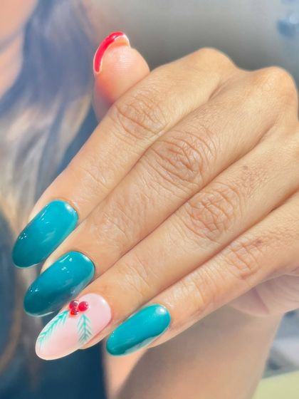 A unique take on Christmas nails. This design features a beautiful teal polish with an accent nail showcasing a hand-painted holly branch and a fun Santa hat design on another.