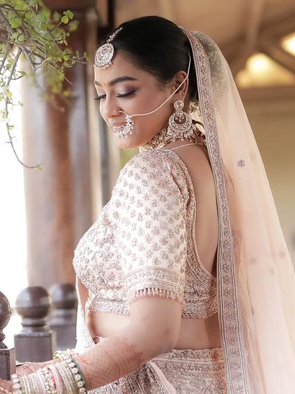 A candid moment of our morning bride. The soft pastel lehenga and subtle makeup create a look of timeless elegance.