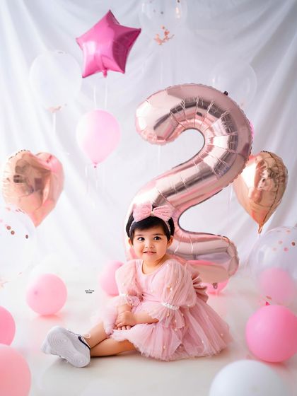 A sweet, seated portrait among the balloons for her second birthday photoshoot.