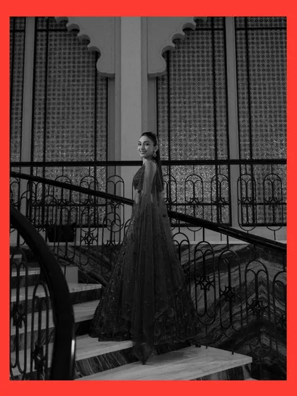 A timeless black and white bridal portrait on a grand staircase. The bride's glance back at the camera is both elegant and engaging, highlighting the beautiful silhouette of her gown.
