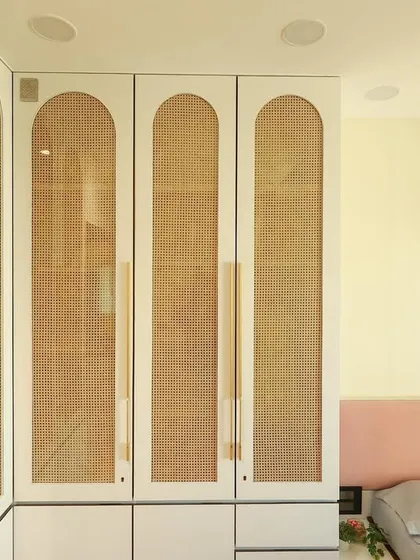 A detail of the arched wardrobe doors with rattan panels, a design that is both contemporary and timeless.