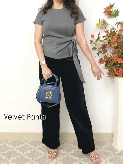 Velvet pants are another fantastic option for winter. They add texture and a touch of luxury to any outfit, as seen here with a simple grey top and a blue handbag.