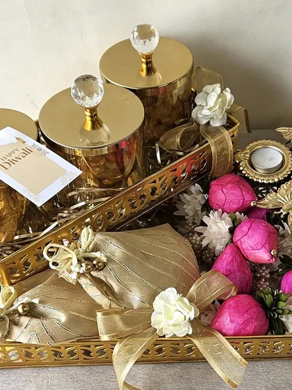 I designed this hamper for those who love gold and glamour. Two ornate trays hold crystal-topped jars and potlis filled with goodies, accented with delicate floral and butterfly details for a touch of whimsy.