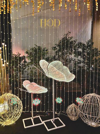 A creative photo spot with illuminated butterfly-shaped seats and a backdrop of fairy lights, perfect for a whimsical and glamorous event theme.