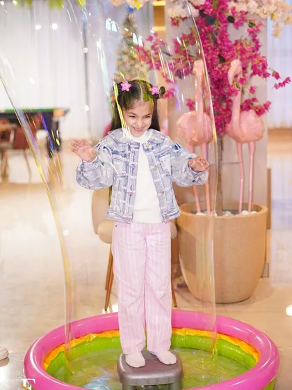 A little girl mesmerized by a giant bubble at a Barbie-themed party. We incorporate fun activities and entertainment to keep the children engaged and delighted.