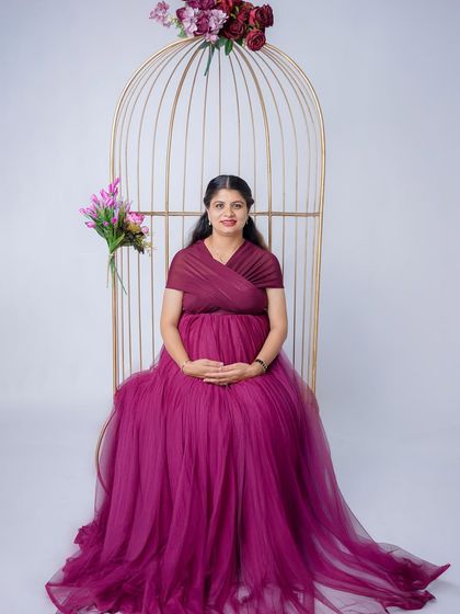 A stunning portrait in a rich purple tulle gown. The mom-to-be is seated in our golden birdcage, creating an elegant and regal composition.
