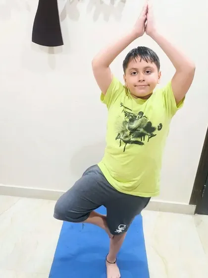 A young student finds his balance in tree pose (Vrikshasana). Yoga helps kids develop balance, concentration, and a deeper connection with their bodies.