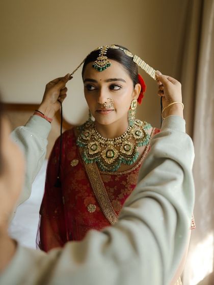 This image captures the final moments of getting ready. You'll learn how to create a classic red bridal look that is both traditional and timeless, complete with a sleek bun and radiant skin.
